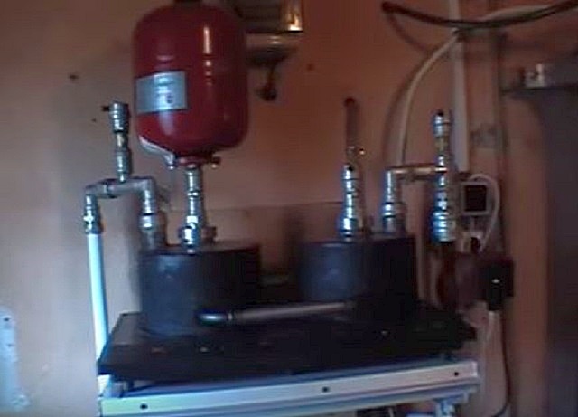 Самодельный «котел» с горизонтально расположенной индукционной панелью и размещенными на ней «кастрюлями»-теплообменниками из ферромагнитного материала.