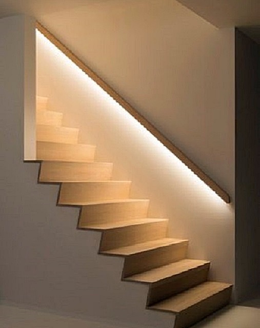 Светодиодная лента, наклеенная под поручни, выгодно декорирует область лестницы, давая мягкий свет на ступени, а также оригинально разделяя стену на более светлый и темный участки.