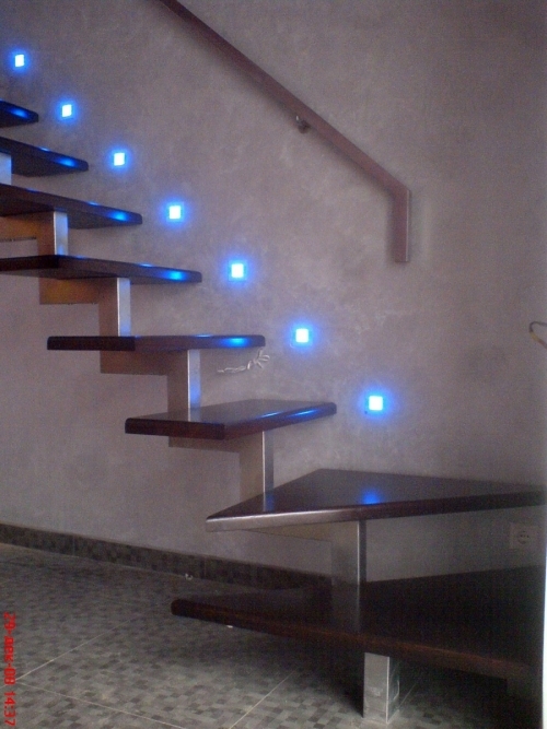 Точечные светильники так же, как и светодиодные ленты могут освещать лестницу разным цветом. Кстати, подниматься по такой лестнице, не имеющей внешнего ограждения, в потемках — весьма рискованное дело