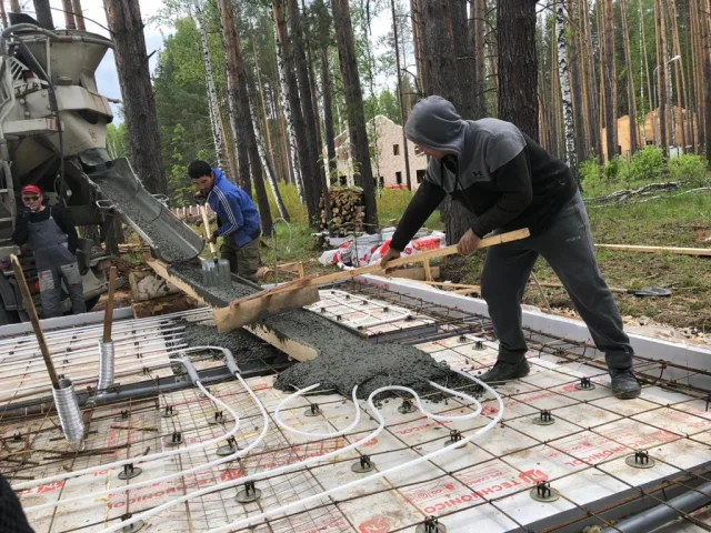 Рабочие аккуратно распределяют раствор так, чтобы не повредить нагревательный контур