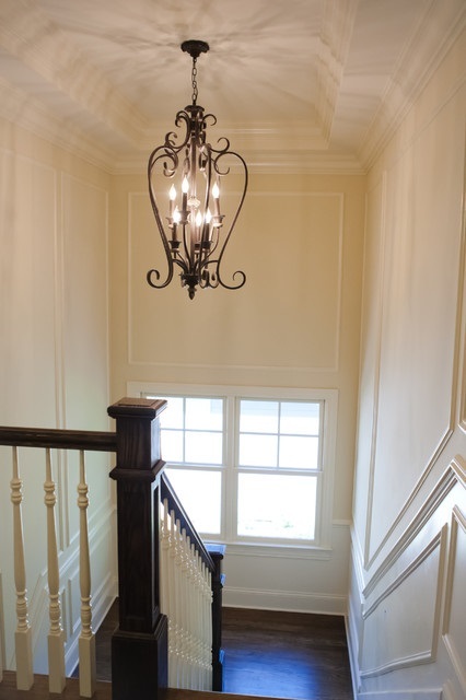 Если над лестничным маршем имеется высокий потолок, то освещение можно организовать и с помощью оригинальной люстры, гармонирующей со стилевой отделкой интерьера