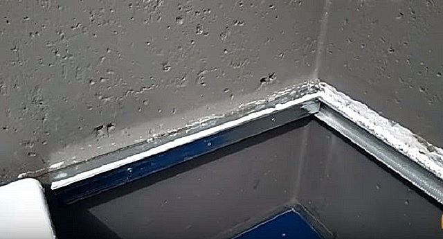 Нанесение герметика на закрепленный на стенах металлический профиль.