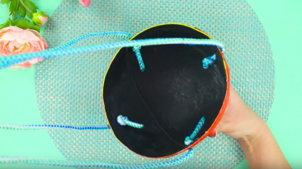 Через отверстия продевают толстые шнуры и фиксируют при помощи узлов