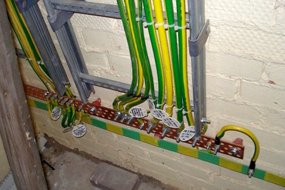 Пример открытой установки главной заземляющей шины на стене помещения. Обратите внимание: все подключенные к ней провода – промаркированы.